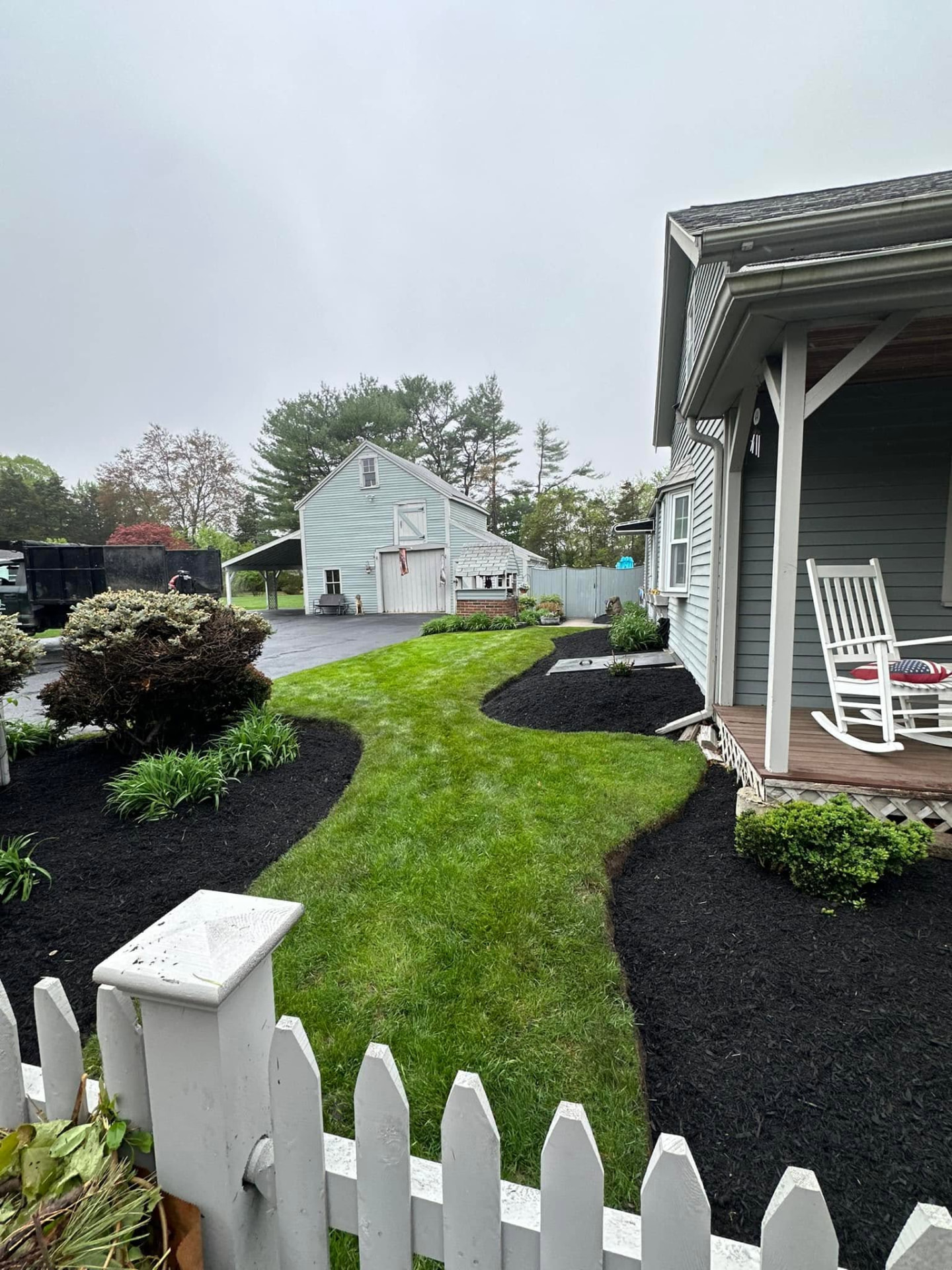 Curved garden beds edged and filled with fresh black mulch